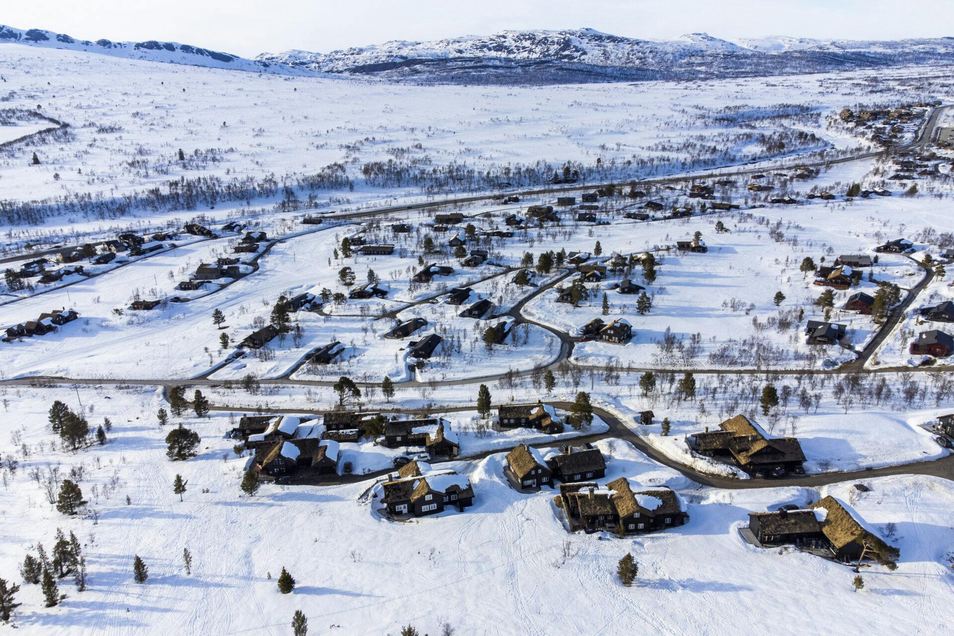 Et dronebilde av et stort hyttefelt i et snødekt landskap på fjellet.